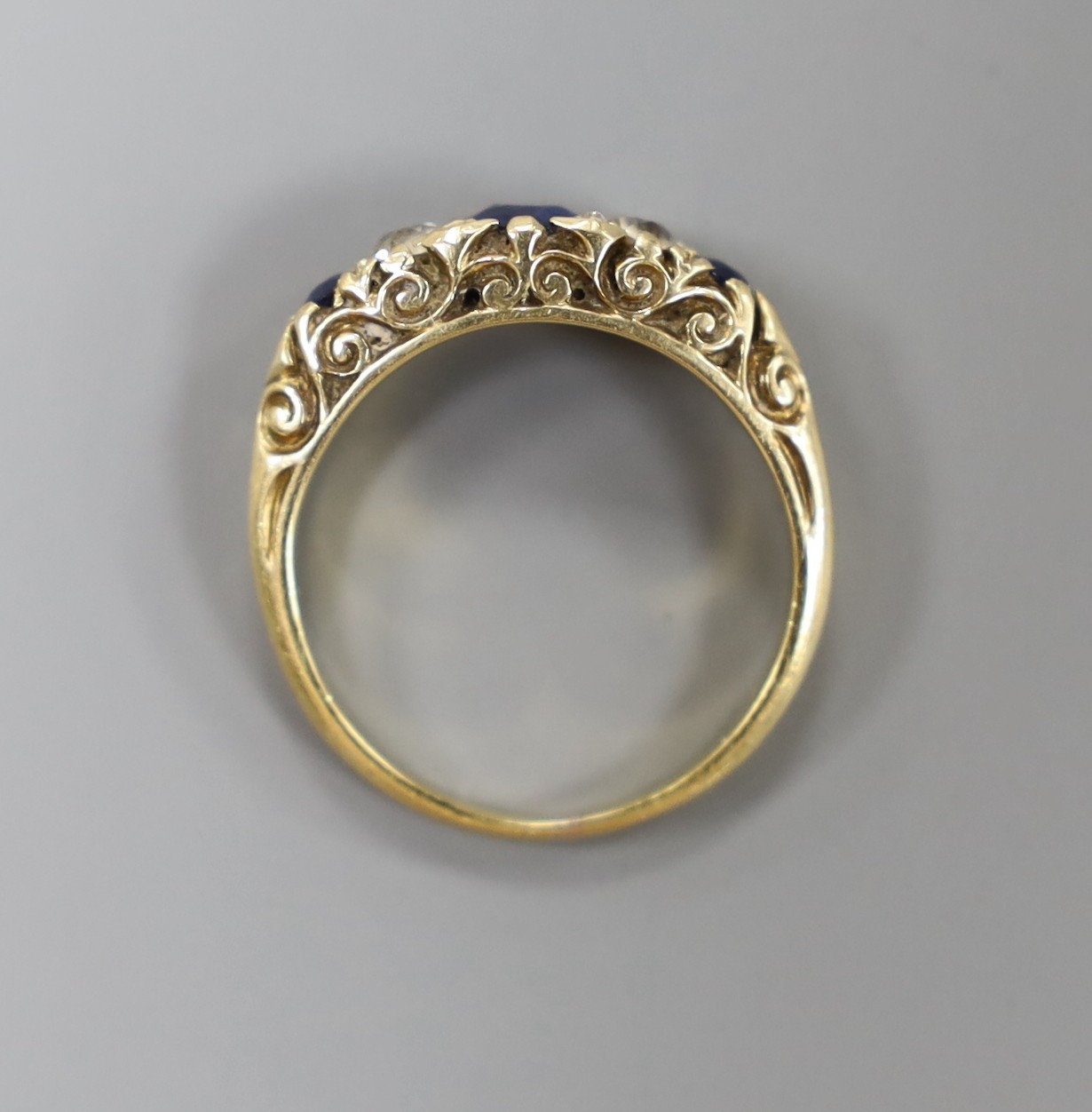 A yellow metal, three stone sapphire and two stone diamond set half hoop ring, with carved setting, size K, gross weight 3.6 grams.